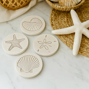 Set of coasters with shell and starfish designs on a marble surface with a woven basket and starfish.
