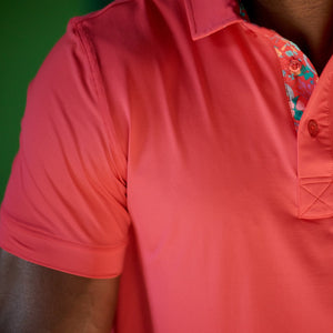 Close-up of a person wearing a red polo shirt with floral embroidery on the chest.