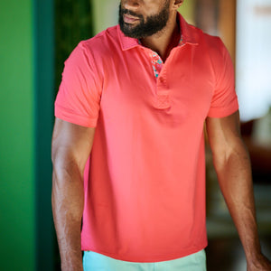 Man wearing a red polo shirt and light blue shorts indoors.