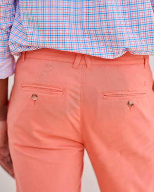 Coral pants with a checkered shirt on a neutral background
