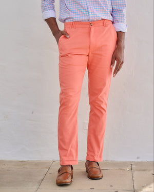 Person wearing coral pants and a checkered shirt against a plain background