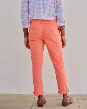 Person wearing a checkered shirt and coral pants against a plain background