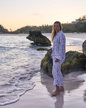 Woman standing on a beach with ocean and rocks in the background