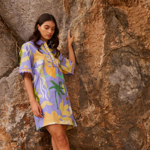 Woman in a colorful dress standing against a rocky wall