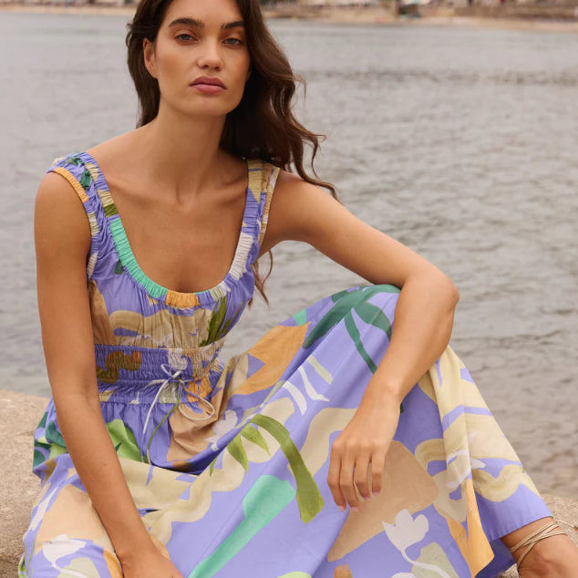 Woman in a colorful dress sitting by a waterfront