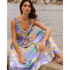 Woman in a colorful dress sitting by a waterfront