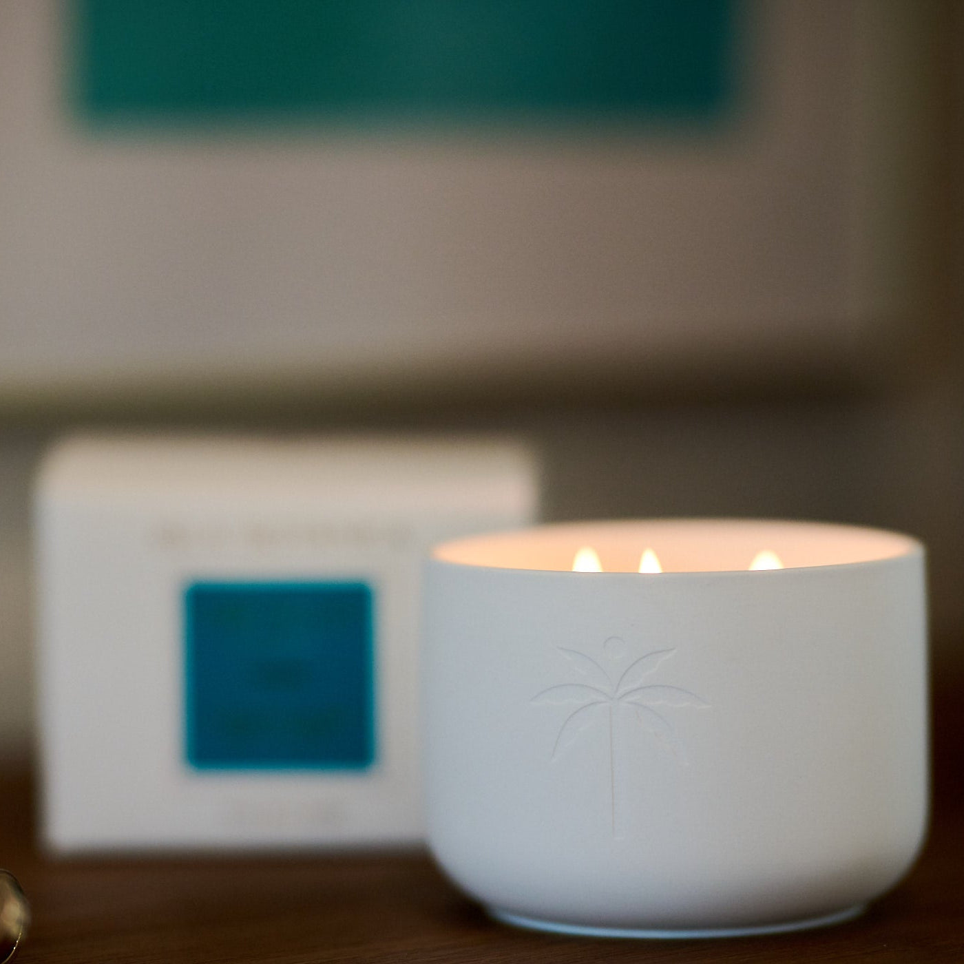 White candle in a decorative holder on a table with a blurred background