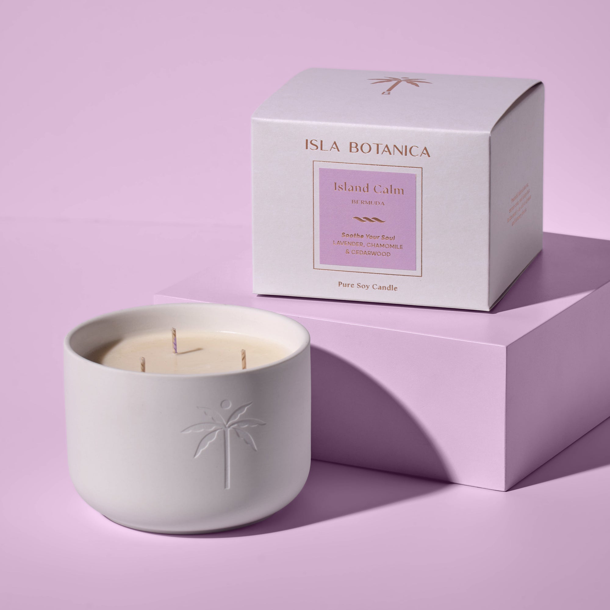White candle in a textured container with a matching box on a light purple background