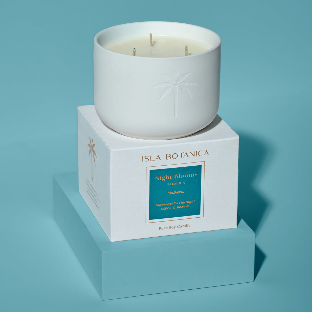 White candle in a box with 'Isla Botanica' branding on a blue background