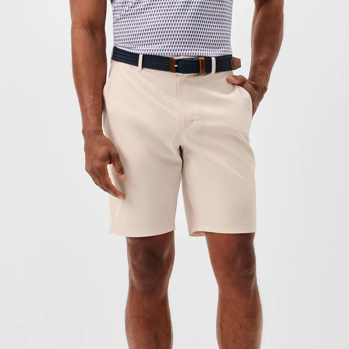 Person wearing beige shorts, navy shoes, and a checkered shirt on a white background