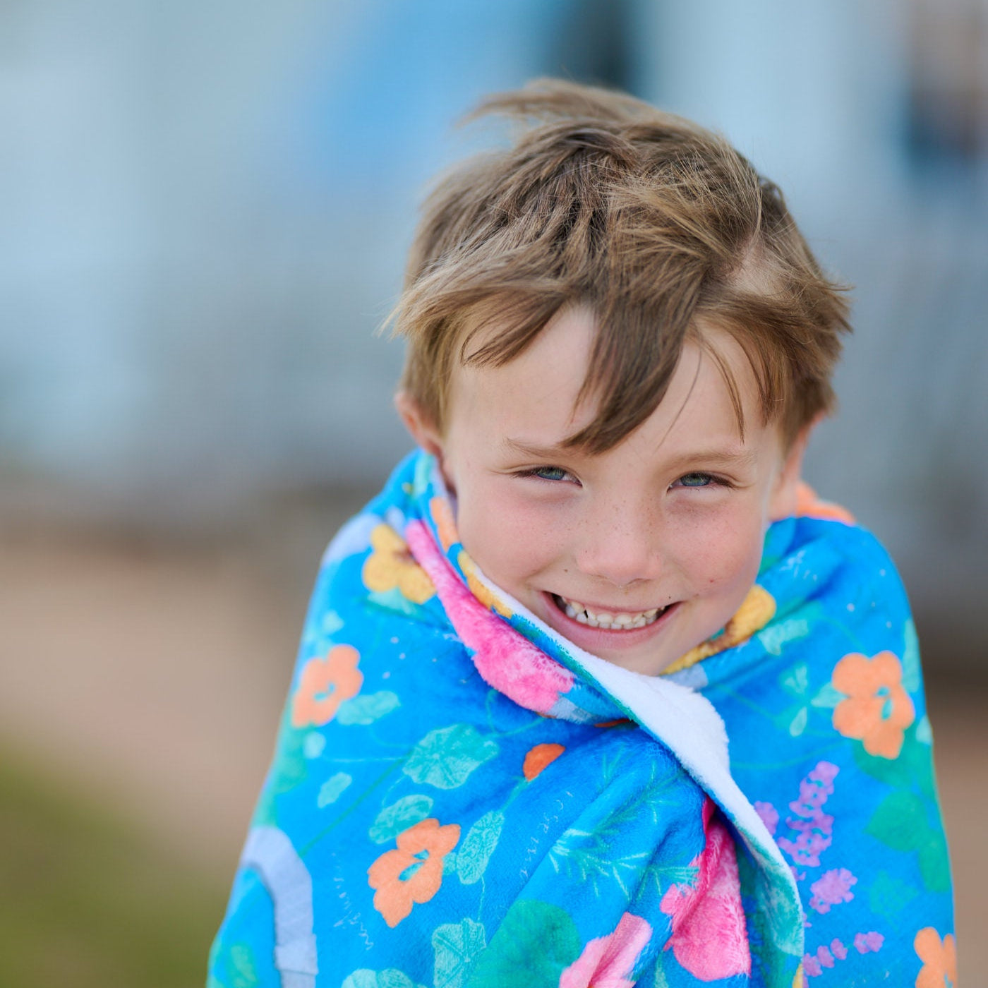 Child wrapped in a colorful towel with floral patterns outdoors