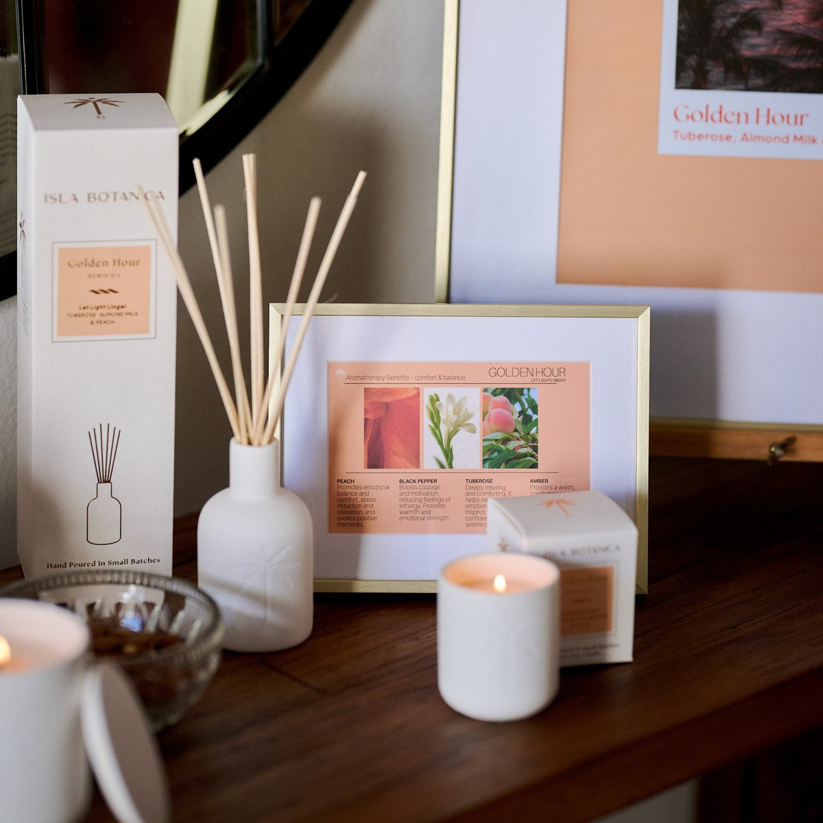 Decorative setup with diffuser, candles, and framed artwork on a wooden surface.