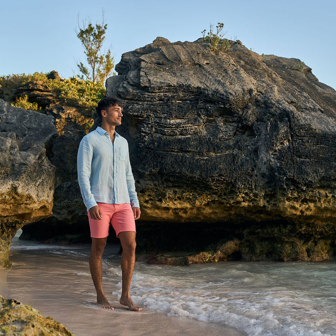 Man standing on a rocky beach with cliffs in the background
