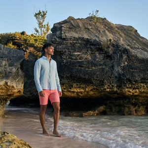 Man standing on a rocky beach with cliffs in the background