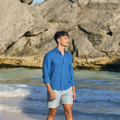 Man standing on a beach with rocky outcrops and ocean waves in the background