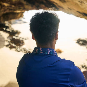 Person sitting under a natural rock archway on a beach