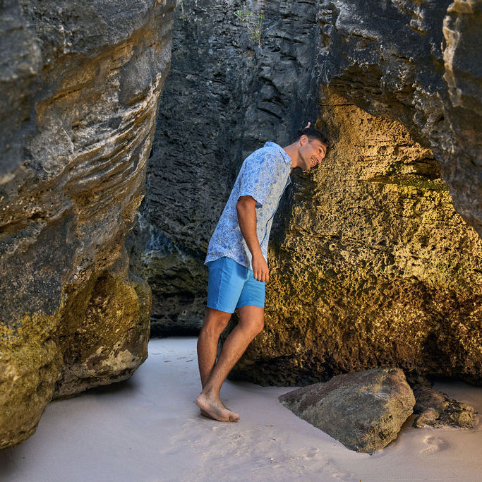 Man standing in a natural rock formation on a beach