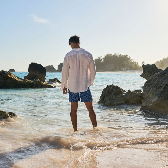 Man standing on a rocky beach looking out at the ocean