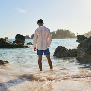 Man standing on a rocky beach looking out at the ocean