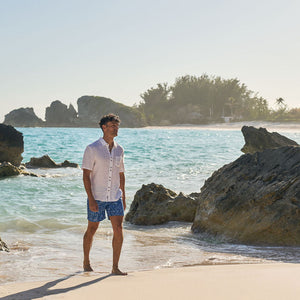 Man standing on a beach with rocks and ocean in the background