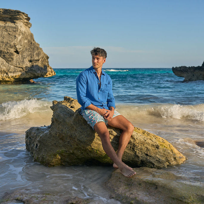 Person sitting on a rock by the ocean with waves crashing around