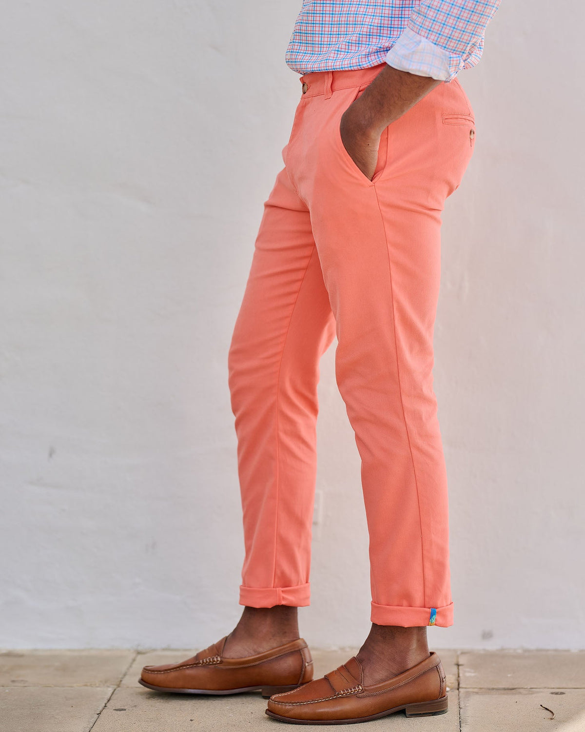 Person wearing coral pants with a cutout design, standing against a light gray wall.