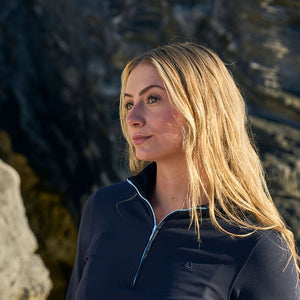 Woman with blonde hair standing against a rocky background