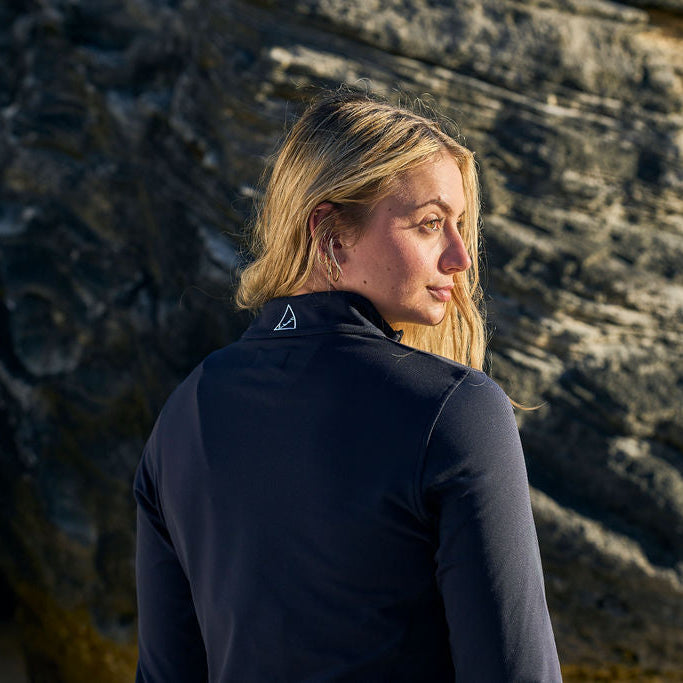 Woman wearing a black jacket standing against a rocky background